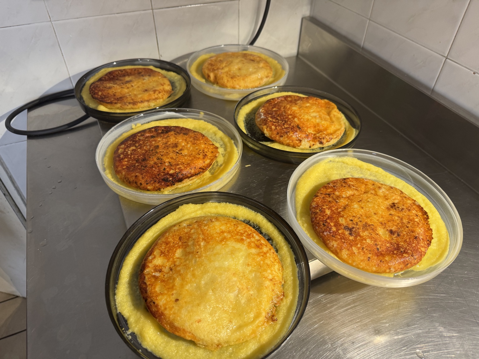 Più frico dorati disposti su polenta