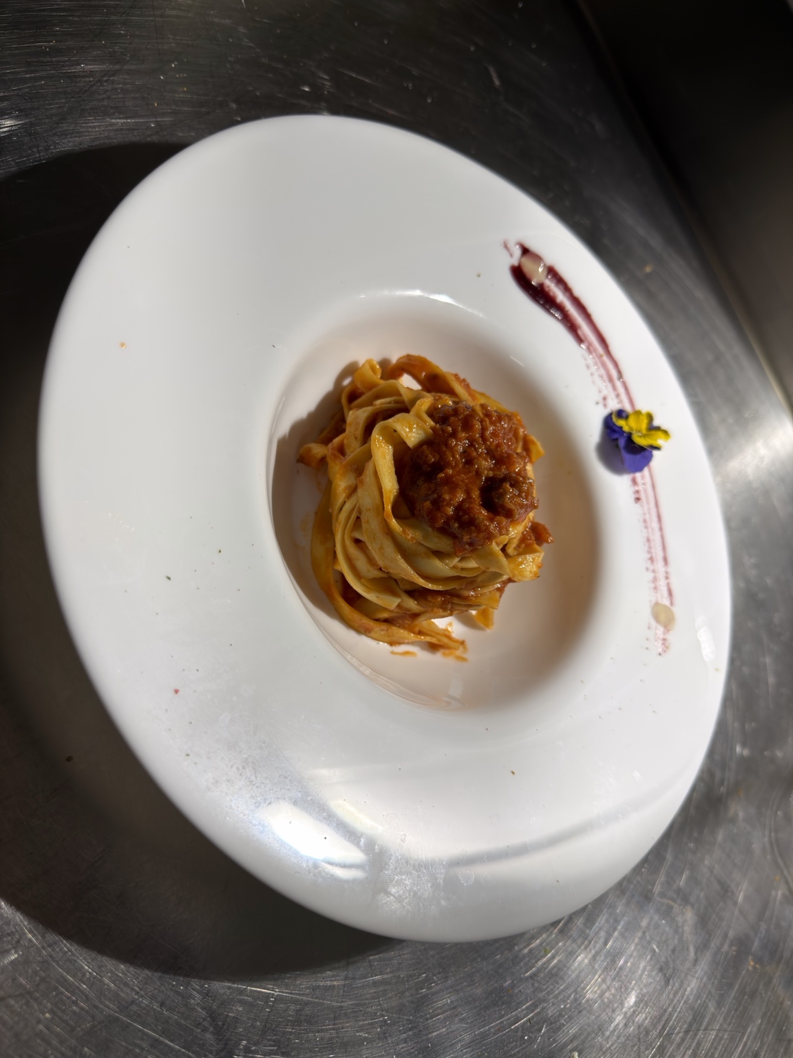 Tagliolini al ragù serviti in piatto bianco